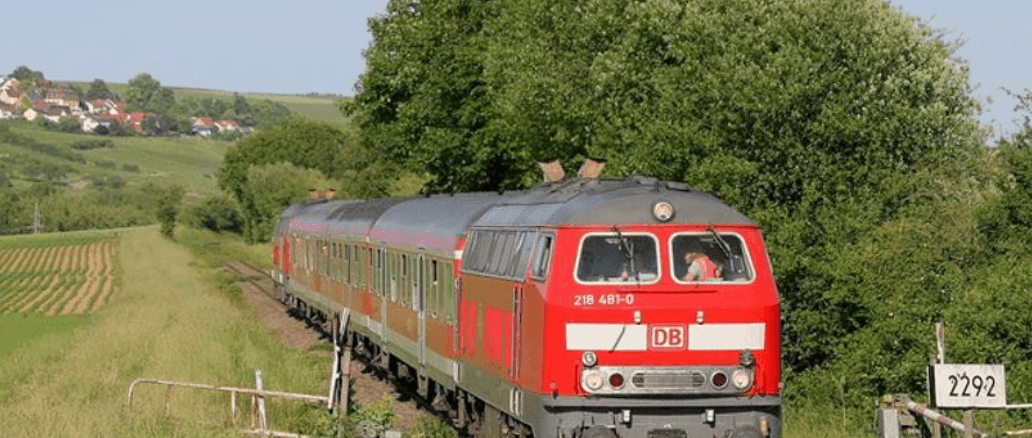 Roter Zug fährt durch grüne Landschaft